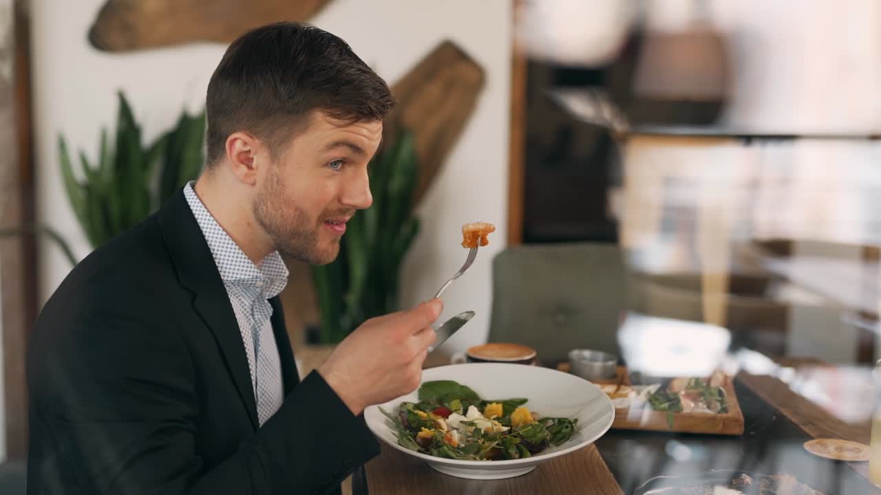 View through the window of a handsome man eating a salad