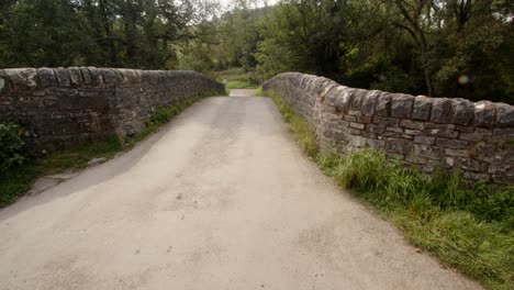 mid shot of road going over the stone bridge at wetton mill