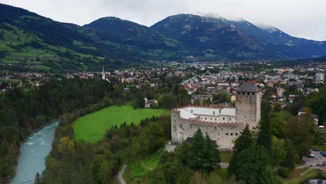 Aerial-View-Of-Castle-Bruck-Beside-River-Isel-In-Austria-With-Town-of-Lienz-In-Background
