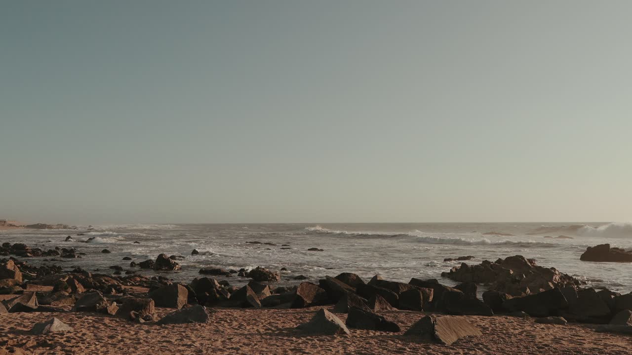 Peaceful rocky beach with ocean waves under warm sunset light