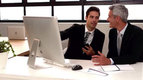 hombres de negocios hablando y apuntando al monitor de la computadora