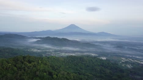 Bosque-En-La-Cima-De-La-Colina-Menoreh-Con-Fondo-De-Vista-Rural-Y-Monte-Sumbing,-Java-Central,-Indonesia