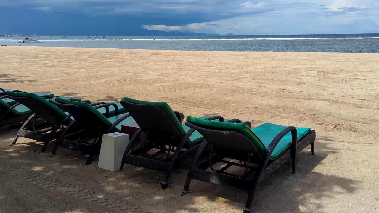 Empty sun lounger chairs with no people on white sand beach in Sanur Denpasar on tropical island of Bali Indonesia