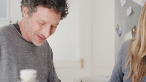 happy young couple eating breakfast together husband sitting with wife at table sharing morning meal in kitchen day in the life 4k footage