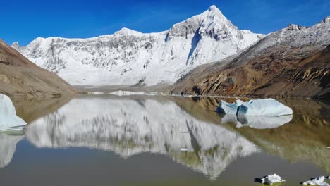 calm glacial lake with icebergs and reflection of cerro san lorenzo’s snowy peak in santa cruz, perito moreno national park, argentina. ascending drone view