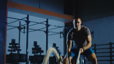 man working out with a battle rope in a gym