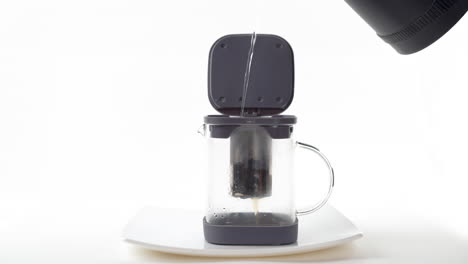 hot water pouring into a french press with coffee grounds on a white sauce