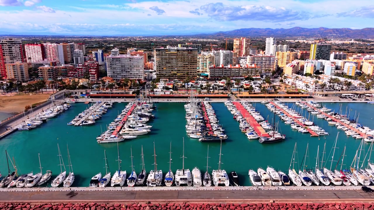 Vista del porto turistico a Castellón, Valencia, Spagna. Angolazione elevata da drone di barche a vela ormeggiate, acqua blu ed edifici della città costiera.