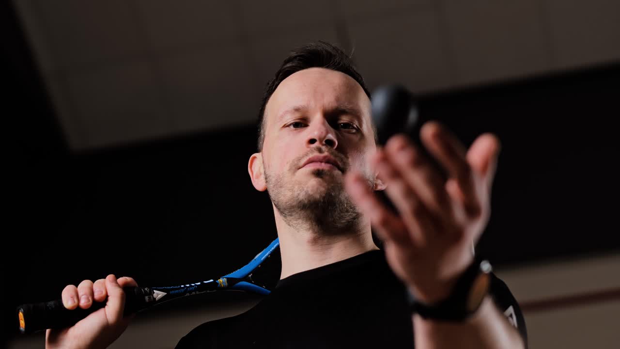 Cinematic squash moment as player tosses black ball before starting intense game