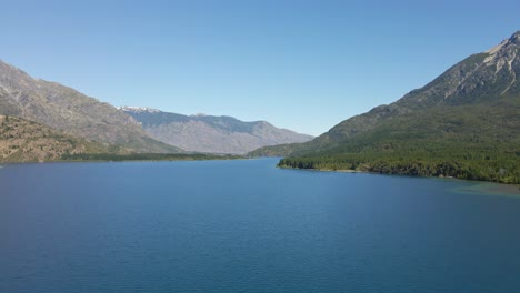 aerial flying over epuyen lake with mountains covered in vegetation in background, patagonia argentina