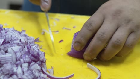 Primer-Plano-De-Las-Manos-Cortando-Cebolla-Roja-En-Una-Tabla-De-Cortar-Amarilla,-Ambiente-De-Cocina