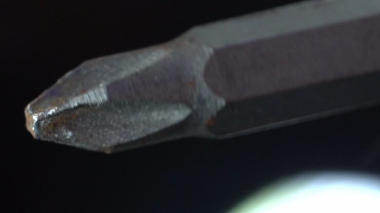 Close-up of a metal Phillips head screwdriver bit on a dark background