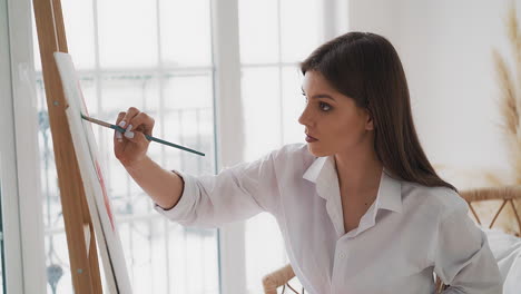 woman draws ornament on canvas sitting in light art studio