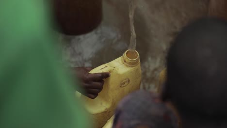 children filling up containers of water in africa at a clean water well in slow motion