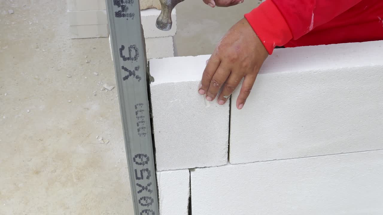 Um trabalhador da construção habilmente assenta blocos no canteiro de obras, exibindo perícia em um projeto de construção prático.