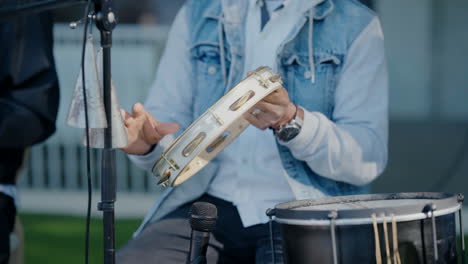 primo piano di un musicista che suona il tamburello e la batteria durante una esibizione all'aperto