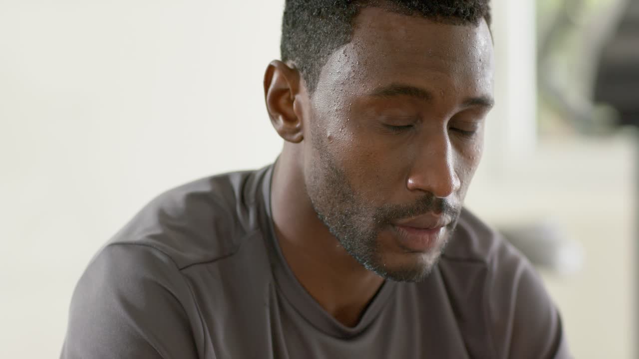 Finishing workout in fitness room, African American man checking smartwatch for heart rate