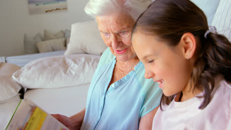 Side-view-of-Caucasian-Grandmother-and-granddaughter-reading-a-book-in-a-comfortable-home-4k