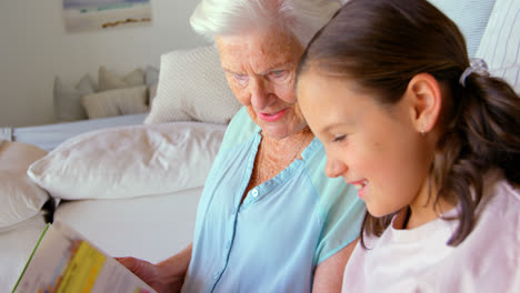 side view of caucasian grandmother and granddaughter reading a book in a comfortable home 4k