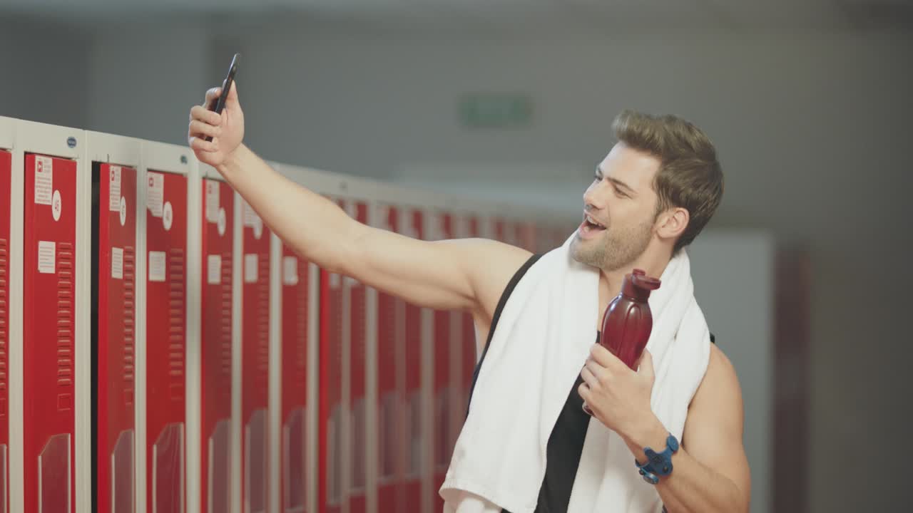Smiling man taking mobile photo after fitness training.