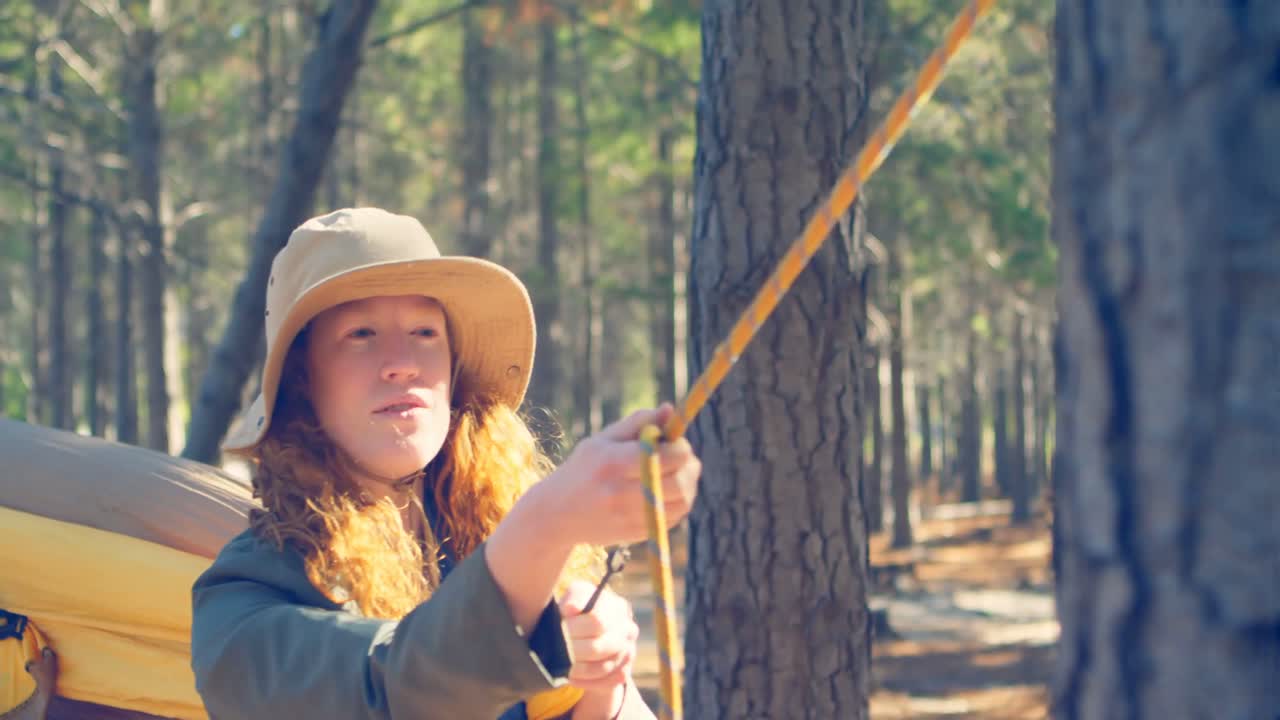 mujer atando una hamaca en el bosque 4k