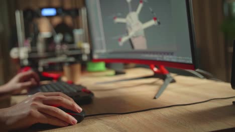 close up engineer's hands working on personal computer and 3d printer, screen shows cad software with 3d prototype of drone delivery
