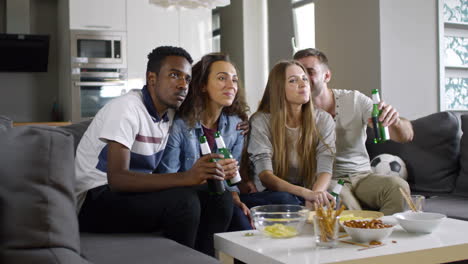 dos parejas sentadas en el sofá, comiendo bocadillos y viendo la televisión