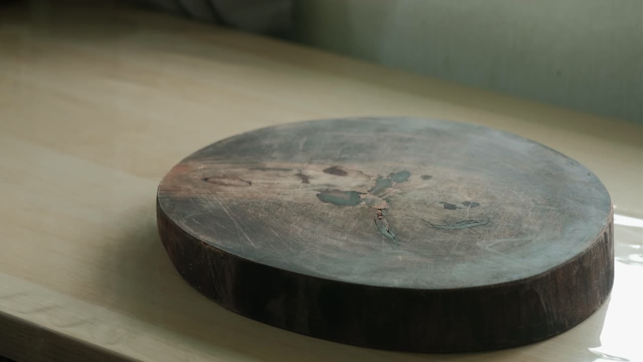 Hands placing round wooden chopping board on a kitchen table. closeup shot