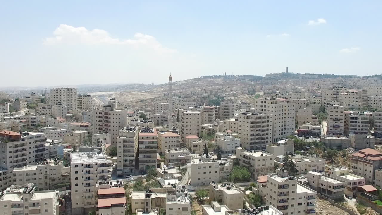 Aerial view of a densely populated Middle Eastern city with a prominent separation wall