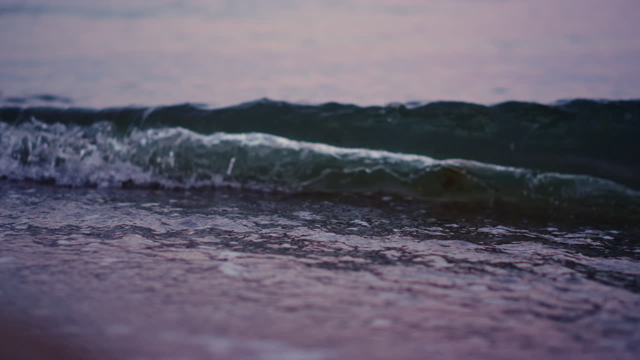 Onde dell'oceano che si infrangono sulla spiaggia sabbiosa al rallentatore. L'acqua del mare ondeggia sulla spiaggia di sabbia.