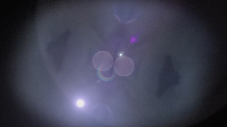 Hypnotic kaleidoscope animation of white and pink bokeh lights on black.
