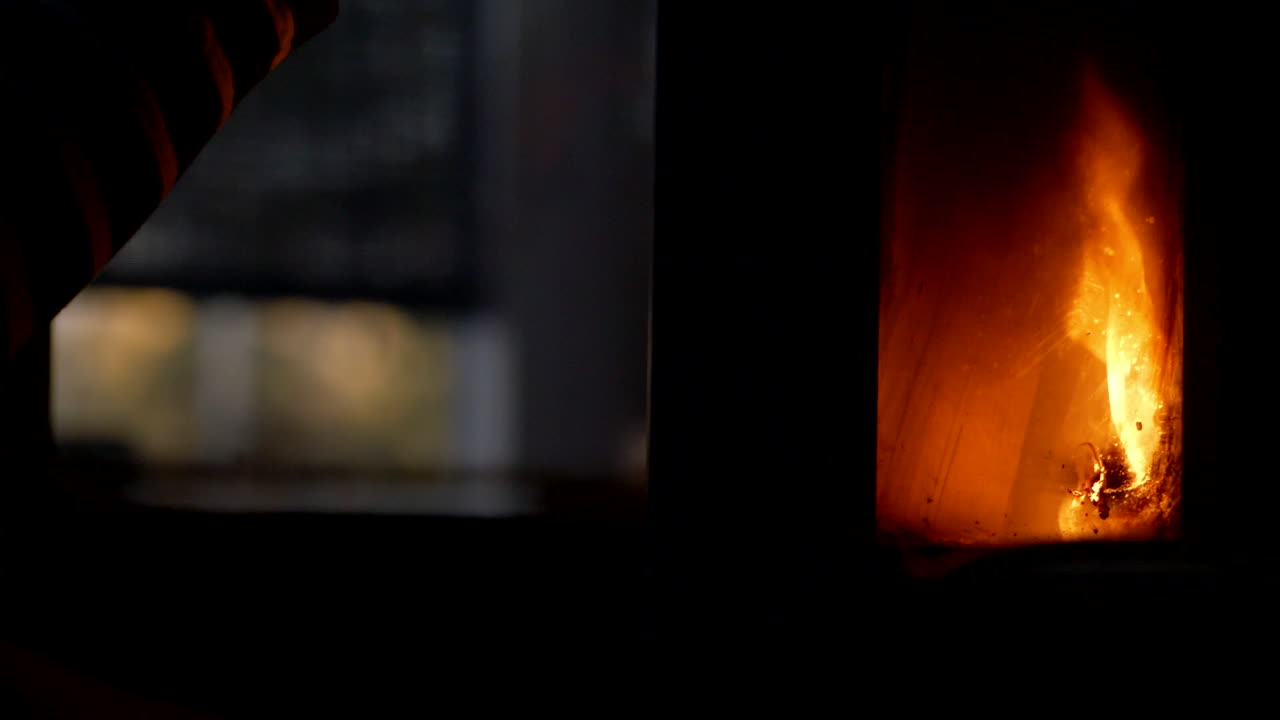 젊은 여성이 거실 주철 난로에서 불을 피우고 슬로우 모션