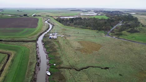 swooping aerial footage flying towards boats showing river estuary and farmland