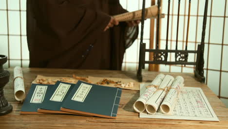 chinese medicinal materials while consulting ancient medical books, actual footage for an advertisement with the theme of traditional medicine, physician