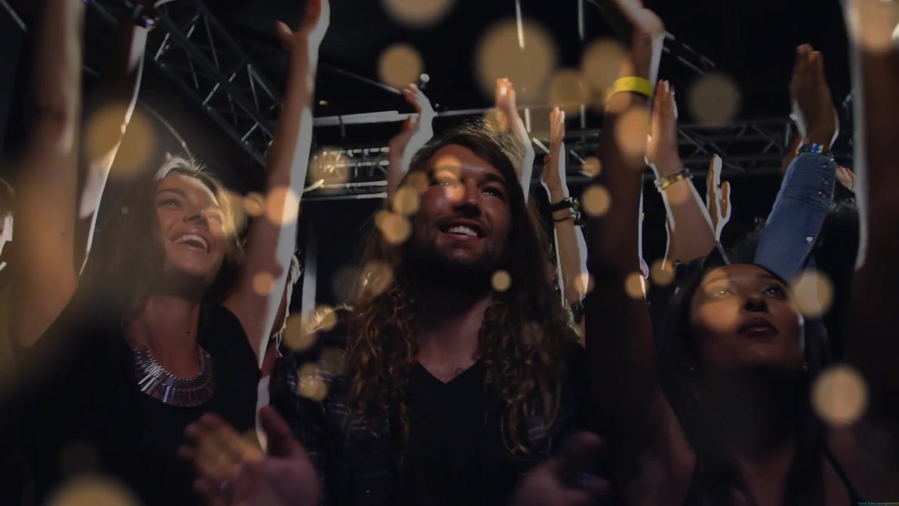 Front-row fans raising hands, clapping at concert, bokeh sweeping crowd as live set sparking cheers