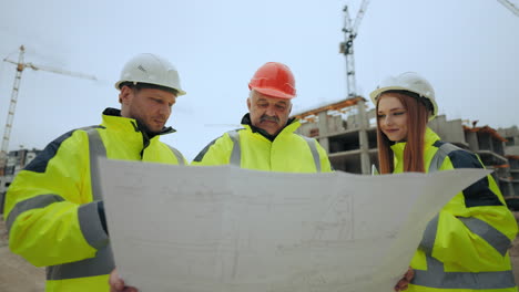 three civil engineers are viewing and discussing construction site plan in modern building area