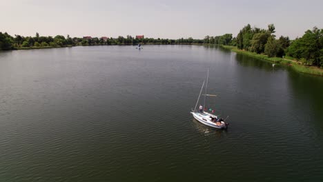 Sailboats-sail-on-a-lake,-distant-drone-parallax-shot