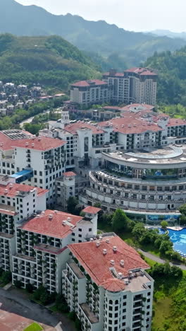 vertical drone shot of in front of a big hotel complex, summer day in china