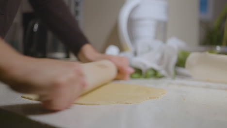 Woman-in-kitchen-uses-rolling-pin-on-dough