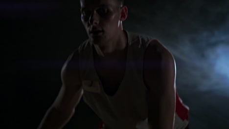 skill dribbling basketball player in the dark on the basketball court with backlit back in the smoke. slow motion streetball