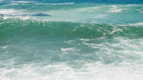 Wave-breaking-on-rock-pebble-beach-on-White-Island,-slow-motion