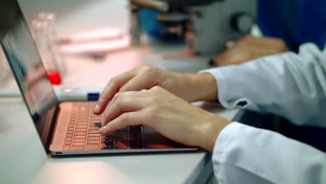 mano del científico escribiendo en el portátil. primer plano de las manos de la científica en el portátil
