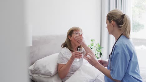 Senior-woman-taking-pills-on-bed-at-home