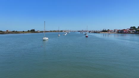 Drone-shot-flying-low-over-water-among-anchored-sail-yachts