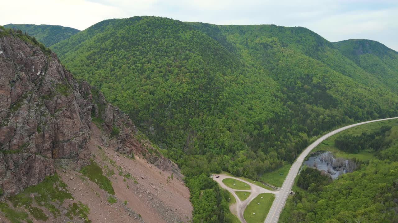 광각 드론 촬영은 캐나다 노바 스코티아의 작은 도로를 둘러싼 거대한 산과 함께 세계적으로 유명한 카보트 트레일 드라이브의 아름다운 산을 드러니다.