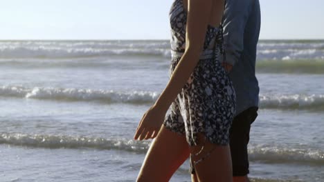 Couple-walking-together-on-shore-at-beach