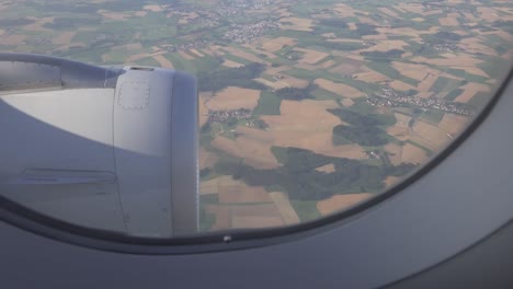 green meadows of european countryside are seen through window of aircraft.