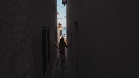 woman walks down a narrow street in villa mediterranea