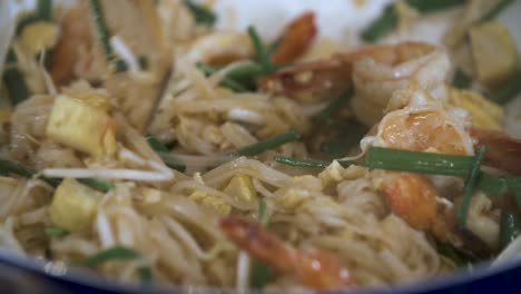 stir fry pad thai noodle dish with shrimp in white pan - close up