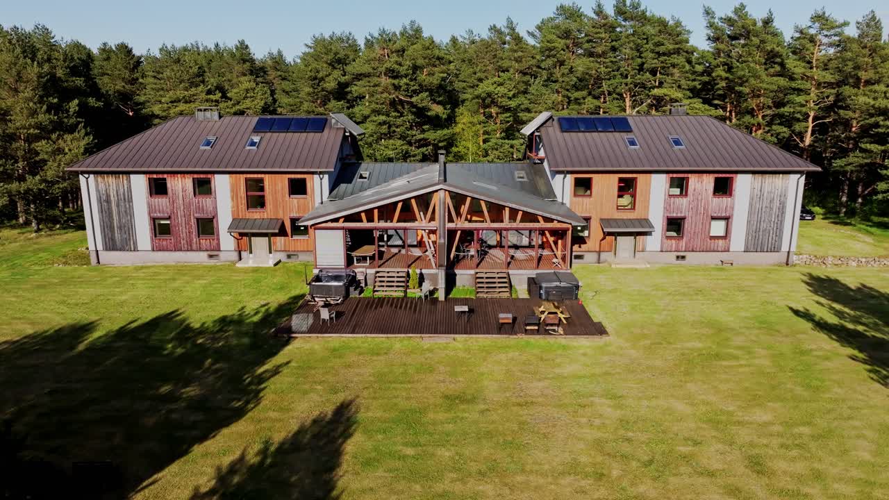Aerial reveal of cozy wooden guesthouse nestled in pine forest in rural Latvia